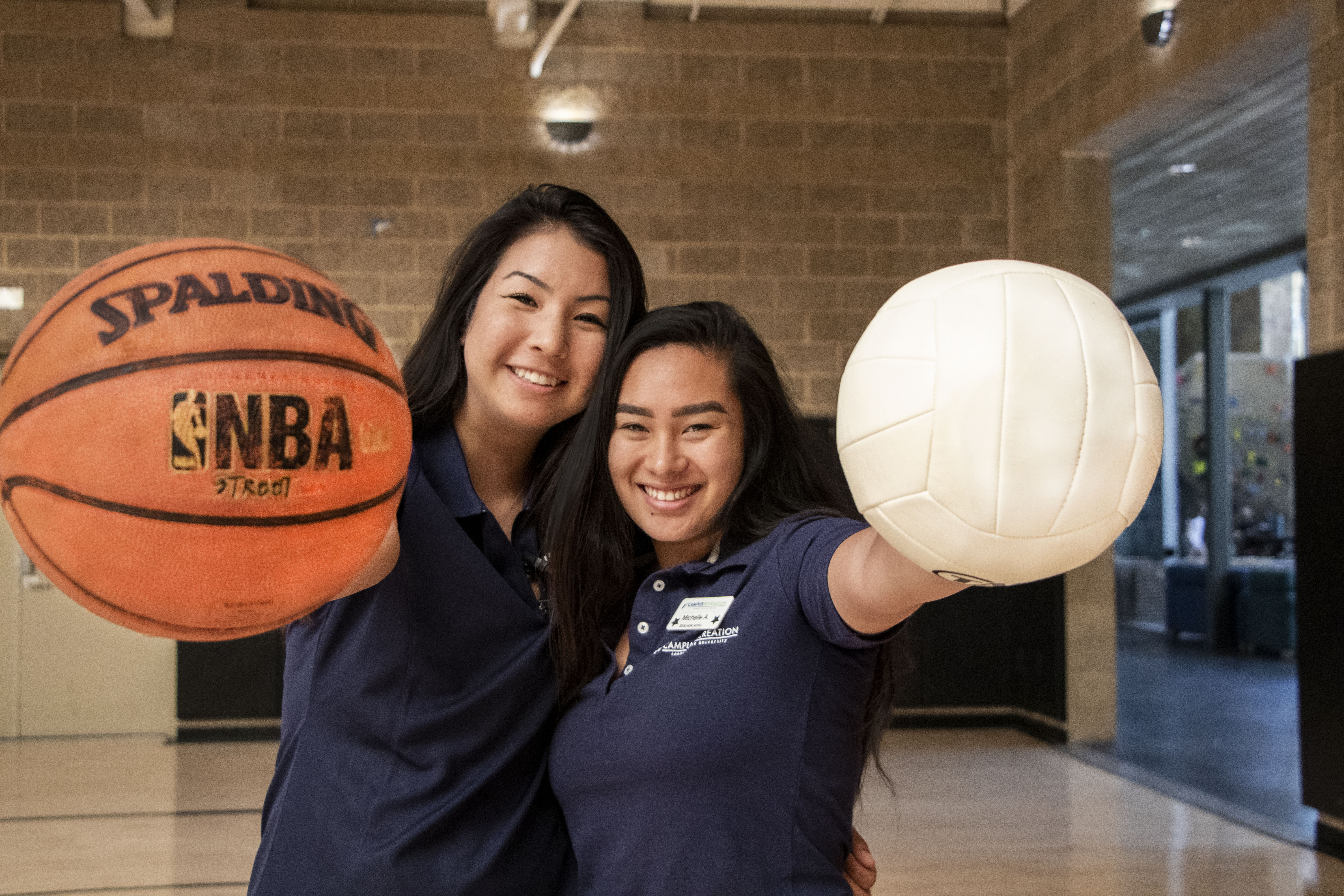 2 students holding a basketball and volleyball