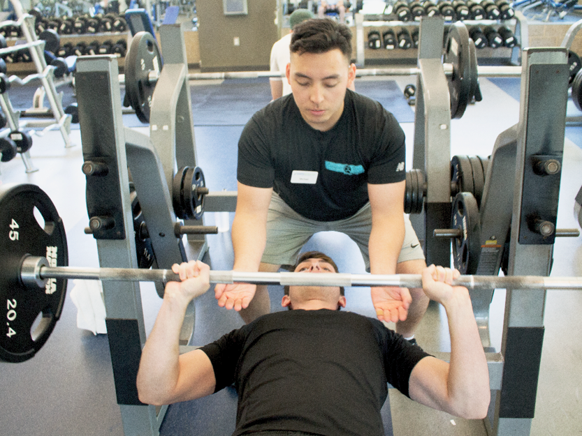 Personal trainer training a student on a weight rack