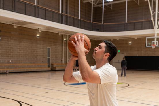 Student throwing a 3 point shot at the basketball court