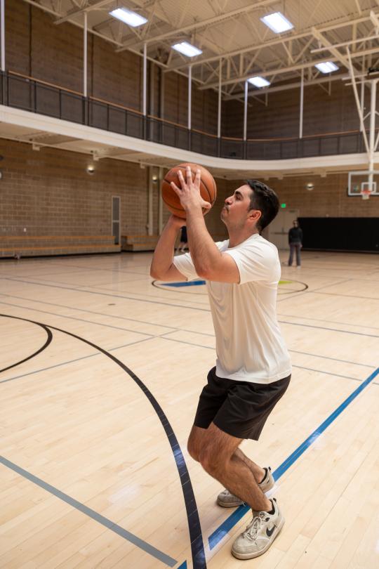 Student throwing a 3 point shot at the basketball court