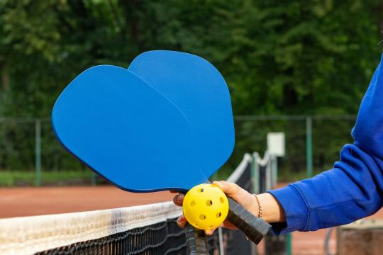 two blue paddles and a yellow ball