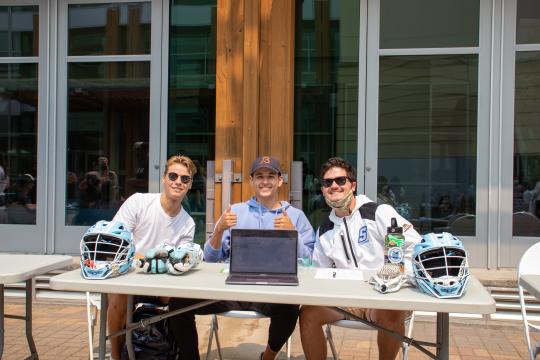 mens lacrosse team smiling at table for REXPO