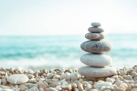 rocks stacked on a beach in front of light blue water