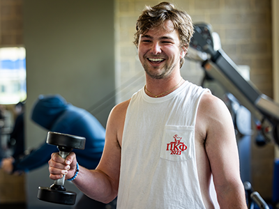 Student lifting dumbell while smiling at the camera