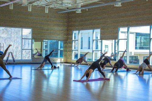 Group yoga class practicing poses in a bright fitness studio.