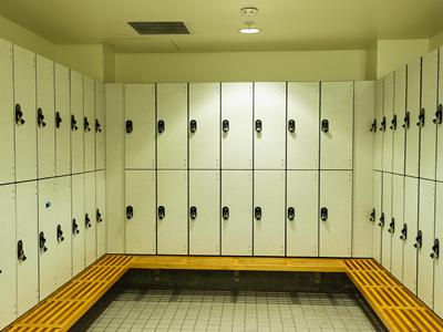 Clean locker room with white lockers and wooden benches.